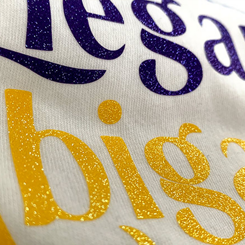 Prisma Sparkleshine Heat Transfer Vinyl in a logo T-Shirt design with sparkly blue and yellow lettering.