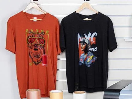 Two DTF printed t-shirts on hangers, a tiger design on orange and an NYC portrait on black